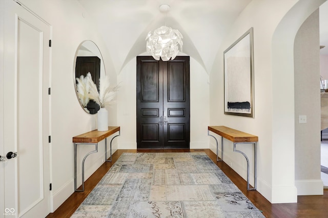 foyer featuring an inviting chandelier, vaulted ceiling, and hardwood / wood-style flooring