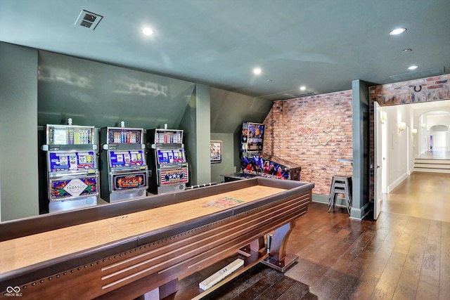 game room featuring dark wood-type flooring and brick wall