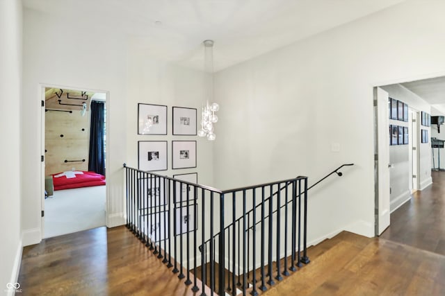 stairway with wood-type flooring and a notable chandelier