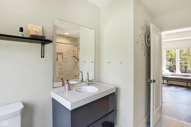 bathroom with a tile shower, vanity, and toilet