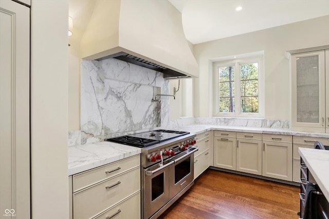 kitchen with light stone countertops, decorative backsplash, dark hardwood / wood-style floors, custom exhaust hood, and double oven range