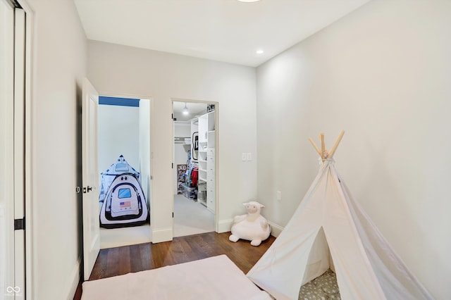 bedroom with a spacious closet and dark hardwood / wood-style floors