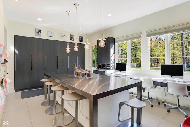 kitchen featuring hanging light fixtures, light tile patterned floors, and a breakfast bar area