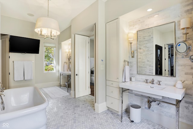 bathroom with an inviting chandelier, tile patterned floors, a tub, and vanity