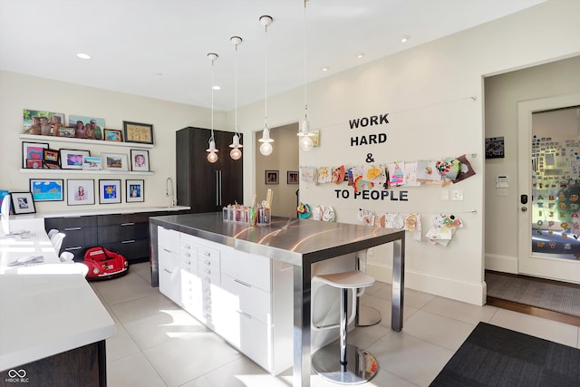 kitchen featuring light tile patterned flooring, pendant lighting, stainless steel counters, white cabinets, and a center island