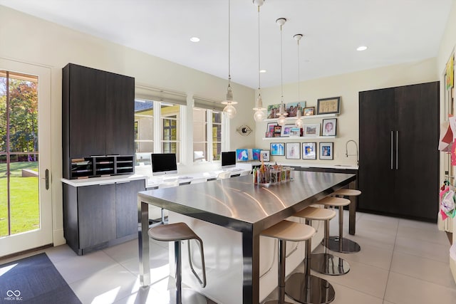 kitchen featuring light tile patterned flooring, decorative light fixtures, a kitchen breakfast bar, and a center island