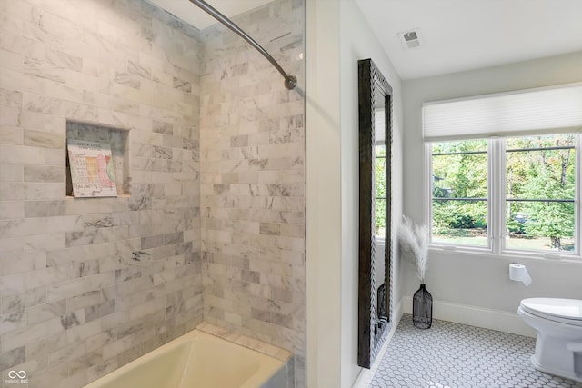 bathroom with tiled shower / bath, toilet, and tile patterned floors