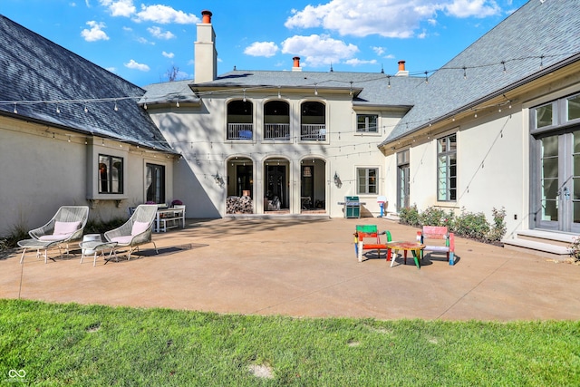 back of property featuring a patio, a balcony, and a lawn