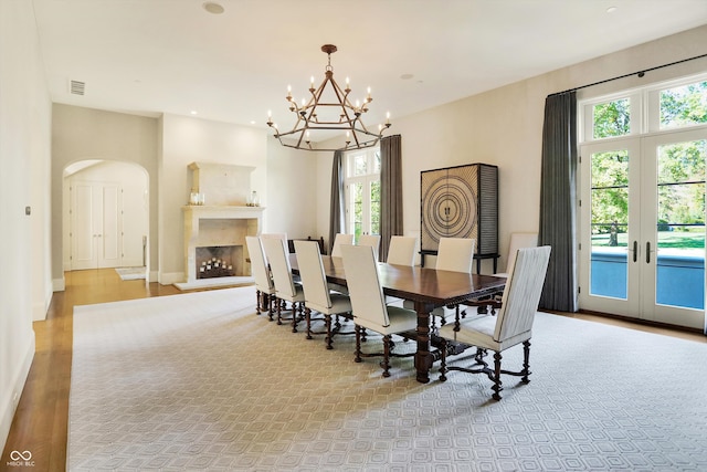 dining room featuring light wood-type flooring, plenty of natural light, french doors, and a chandelier