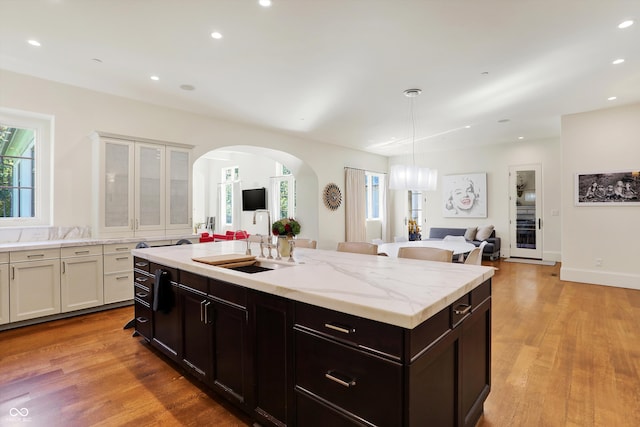 kitchen with pendant lighting, a kitchen island with sink, light hardwood / wood-style floors, and sink