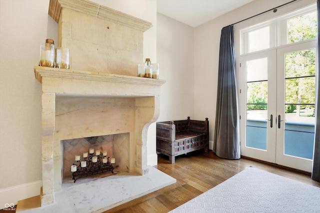 bedroom featuring access to outside, wood-type flooring, french doors, and a high end fireplace