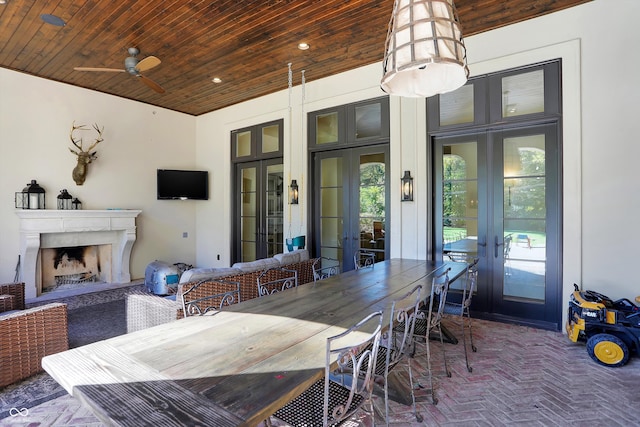 dining space with french doors, an outdoor fireplace, wood ceiling, and ceiling fan