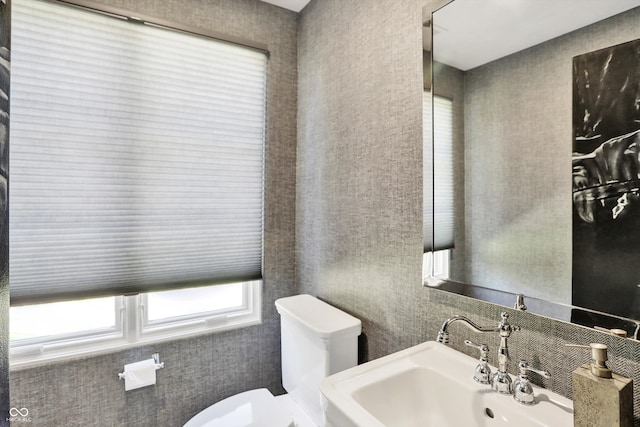 bathroom with sink, tile walls, and toilet