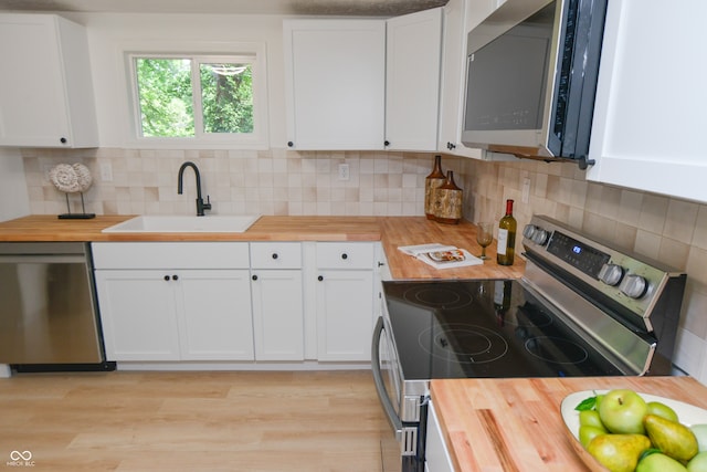 kitchen with butcher block countertops, tasteful backsplash, white cabinetry, and appliances with stainless steel finishes