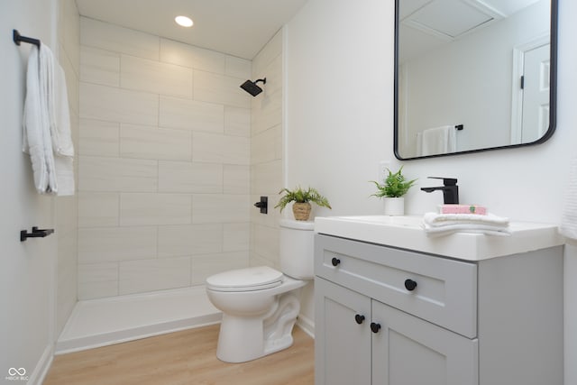 bathroom featuring tiled shower, hardwood / wood-style floors, vanity, and toilet