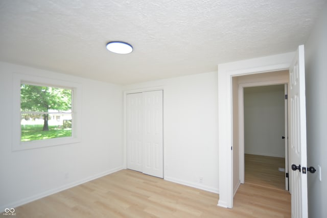 unfurnished bedroom featuring a closet, light hardwood / wood-style flooring, and a textured ceiling