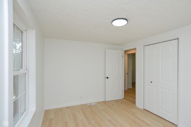 unfurnished bedroom with a closet, light hardwood / wood-style flooring, and a textured ceiling