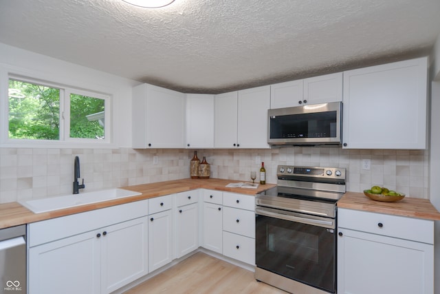 kitchen with stainless steel appliances, sink, tasteful backsplash, and light wood-type flooring