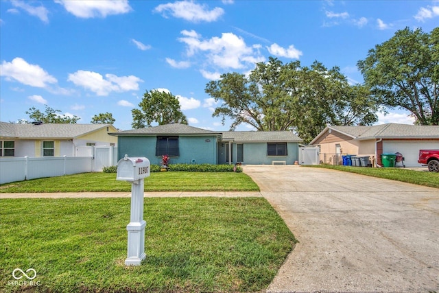 ranch-style house featuring a front lawn, fence, and driveway