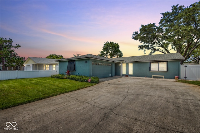 ranch-style home featuring a lawn and a garage