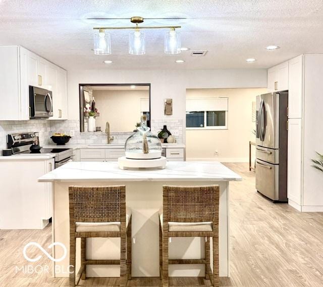 kitchen with a sink, a kitchen breakfast bar, white cabinetry, and stainless steel appliances