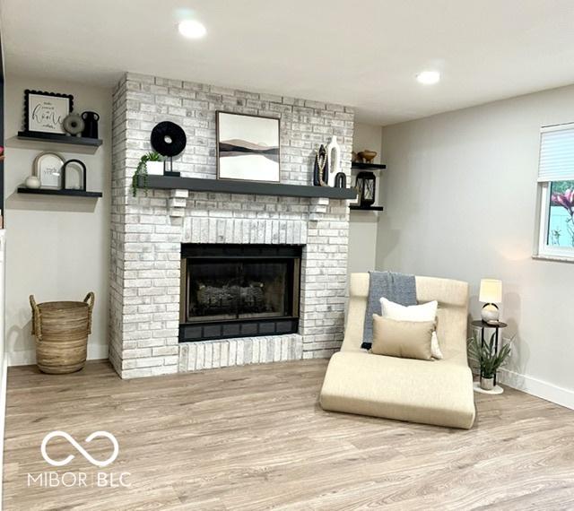 living area featuring a fireplace, recessed lighting, wood finished floors, and baseboards