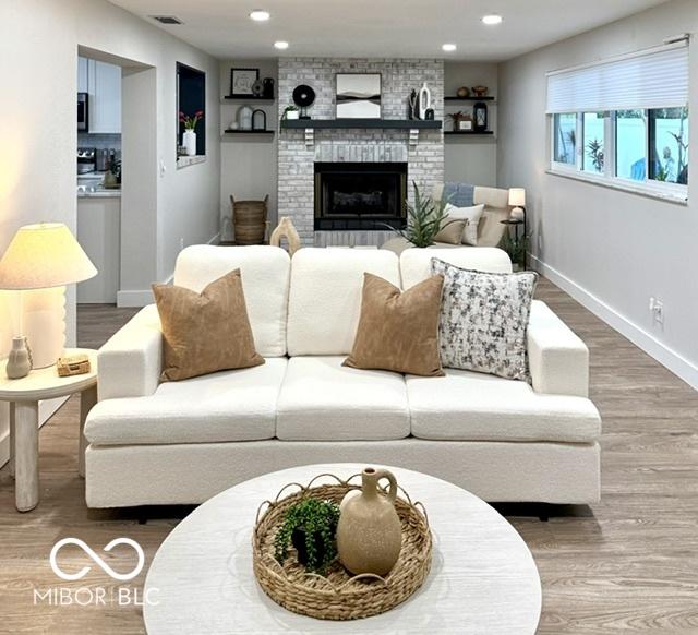 living area with a brick fireplace, recessed lighting, wood finished floors, and baseboards