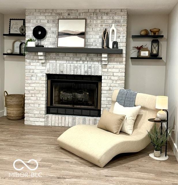 living area featuring a brick fireplace, wood finished floors, and baseboards