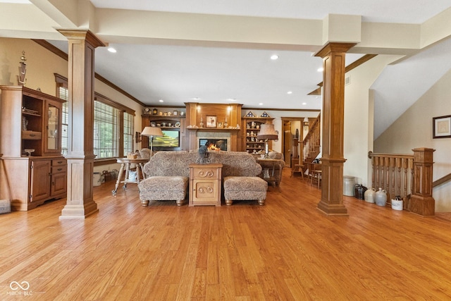 living room with a large fireplace, ornamental molding, and light hardwood / wood-style floors