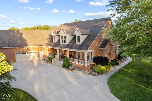 cape cod home featuring a front yard, a porch, and a garage