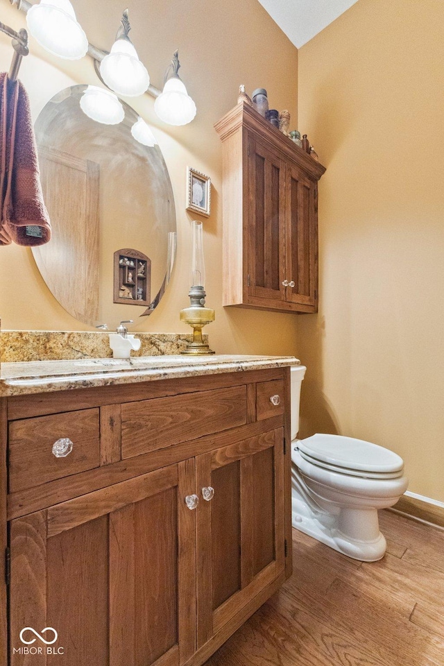 bathroom with hardwood / wood-style flooring, toilet, and vanity