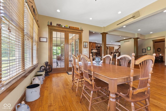 dining area featuring light wood-type flooring, french doors, and ornate columns