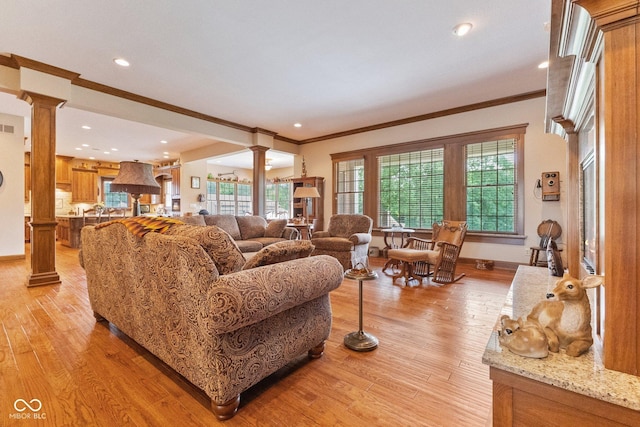 living room featuring decorative columns, light hardwood / wood-style floors, and a wealth of natural light