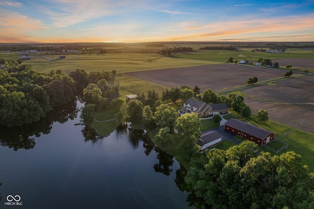 aerial view at dusk featuring a rural view and a water view