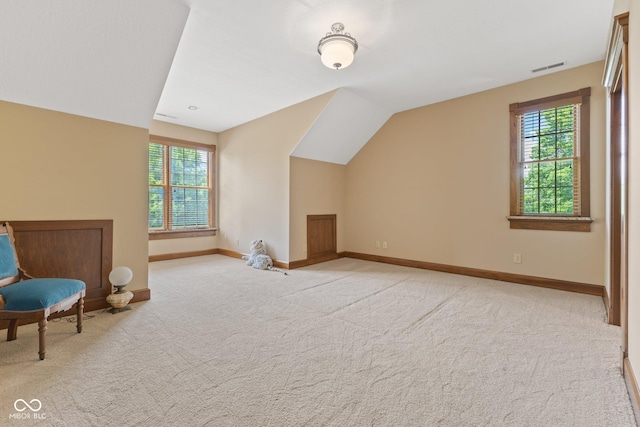 additional living space featuring light carpet, a healthy amount of sunlight, and lofted ceiling