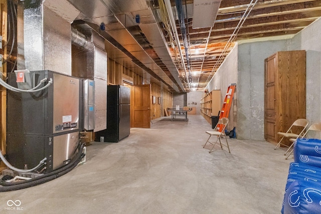 basement featuring heating unit and black refrigerator