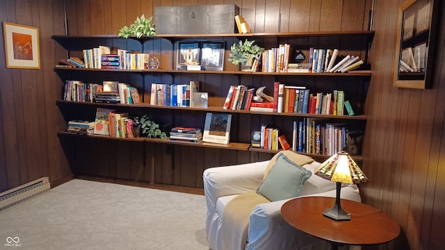 sitting room featuring wooden walls, carpet, and a baseboard heating unit