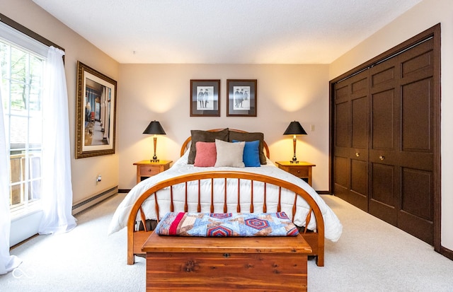 bedroom featuring a baseboard radiator, light colored carpet, and a closet