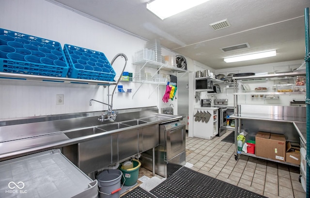 kitchen with white cabinetry, stainless steel electric range oven, stainless steel counters, and light tile patterned flooring