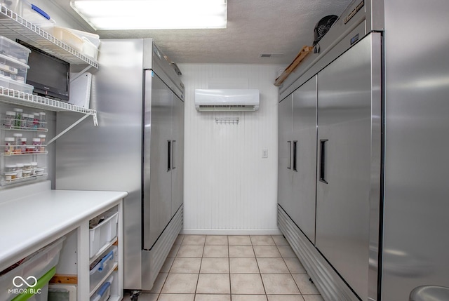 kitchen featuring light tile patterned flooring, a wall mounted AC, stainless steel fridge, stainless steel built in fridge, and a textured ceiling