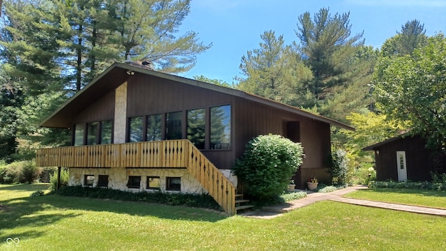 rear view of property featuring a wooden deck and a lawn