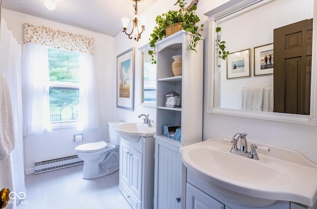 bathroom with vanity, plenty of natural light, baseboard heating, and toilet