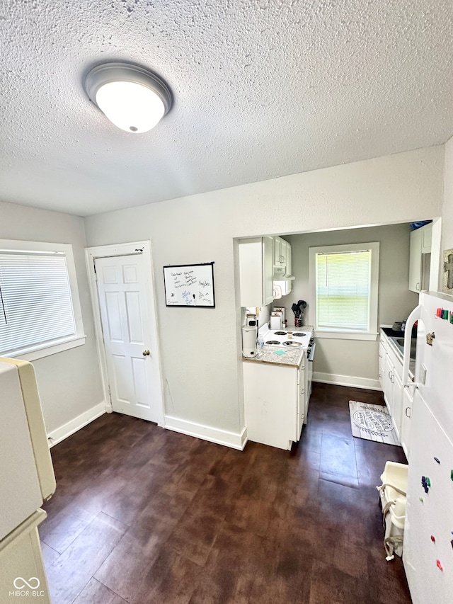 kitchen with white cabinets, white appliances, and a textured ceiling