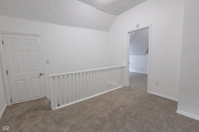 carpeted empty room with a textured ceiling and lofted ceiling