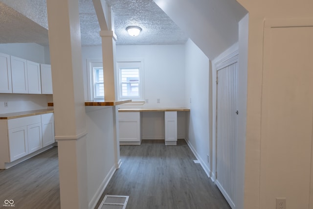 interior space featuring light hardwood / wood-style floors, wood counters, white cabinetry, and a textured ceiling