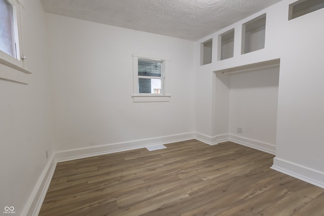 unfurnished room with hardwood / wood-style flooring, a healthy amount of sunlight, and a textured ceiling