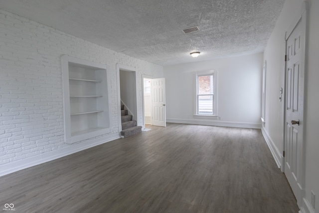 unfurnished living room featuring a textured ceiling, wood-type flooring, and built in shelves