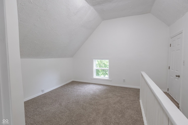 bonus room featuring lofted ceiling, light colored carpet, and a textured ceiling