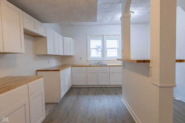 kitchen with white cabinetry, sink, light wood-type flooring, and a textured ceiling