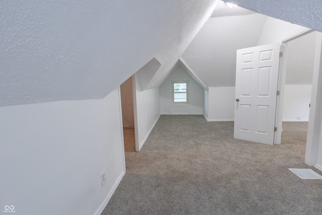 additional living space featuring light carpet, lofted ceiling, and a textured ceiling